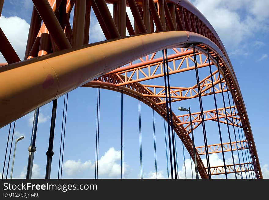 Original orange bridge structure with blue sky and clouds as bacground.