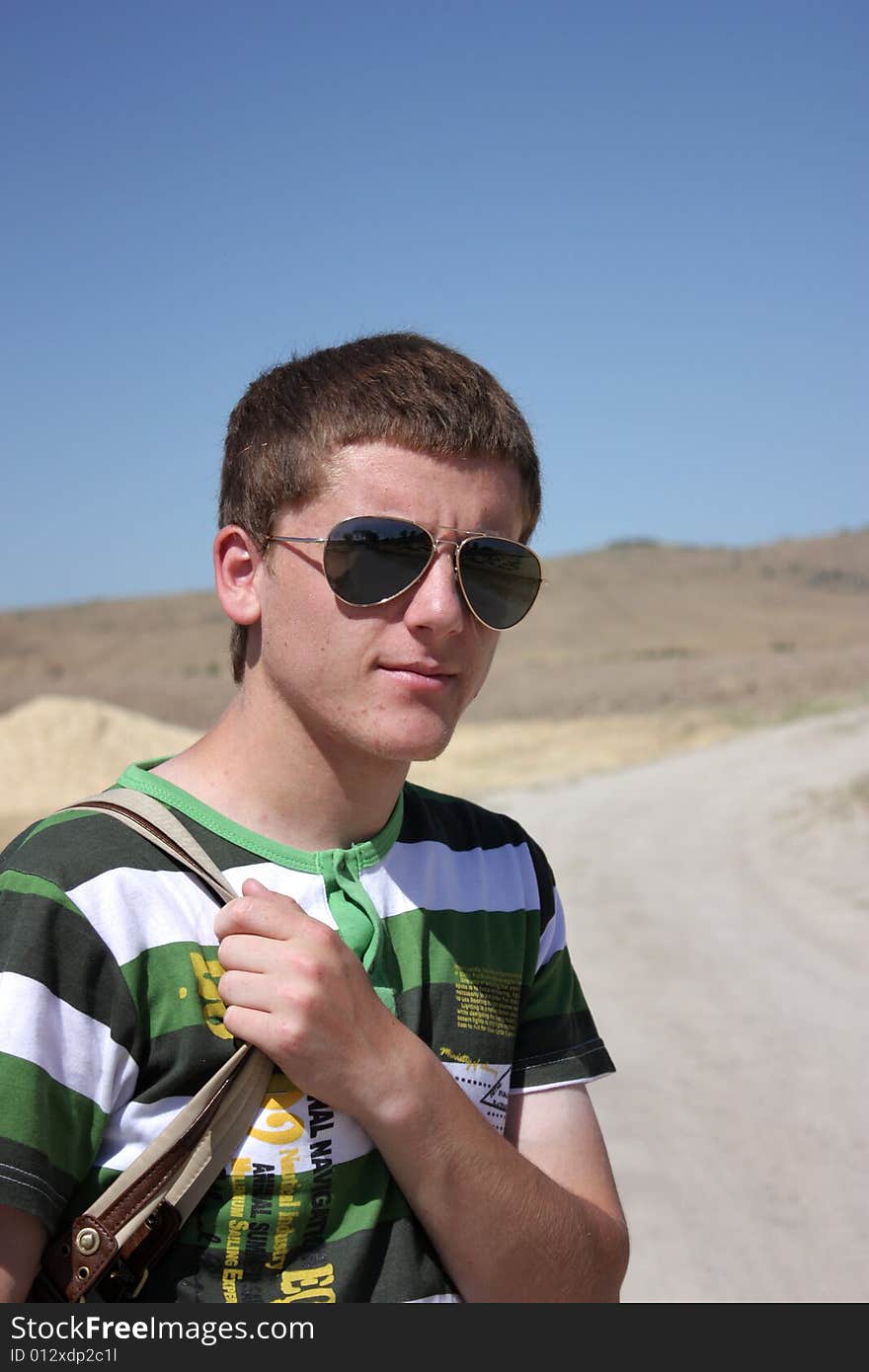 Young boy smiling with eyeglasses and bag.