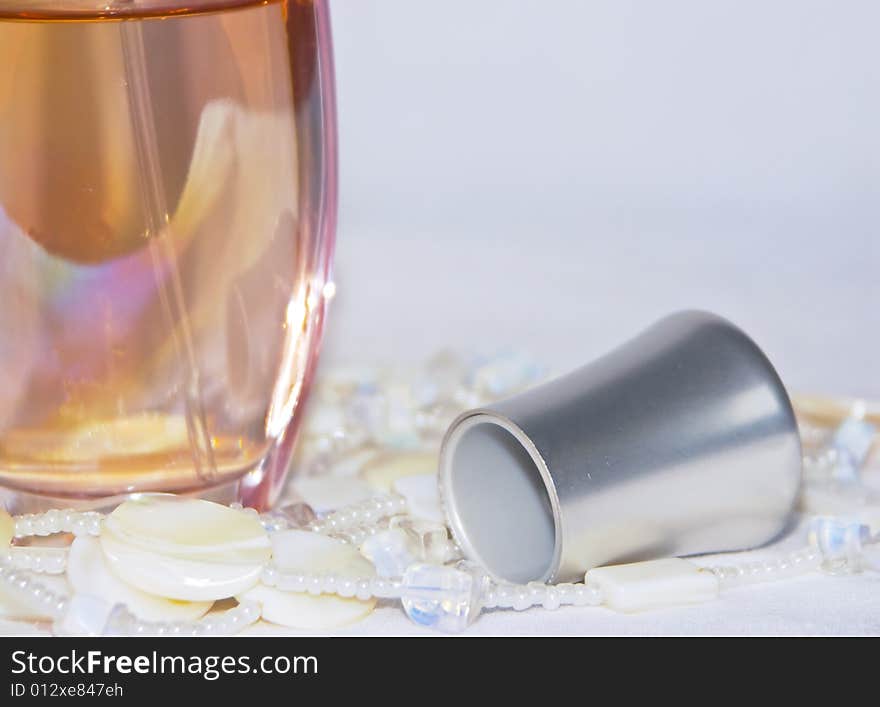 The image of a bottle with perfumery water and the scattered thread of a beads