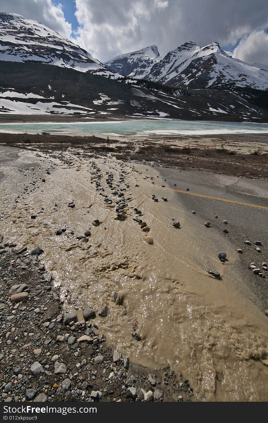 Dirty water overflowing the road and running towards a clear lake. Dirty water overflowing the road and running towards a clear lake.