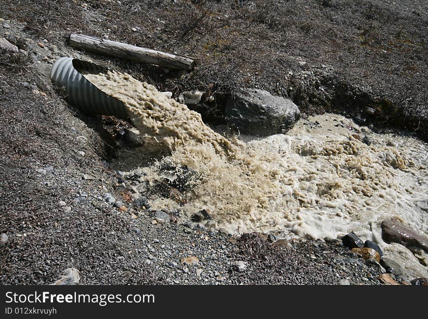 Dirty water running out of a large pipe. Dirty water running out of a large pipe.