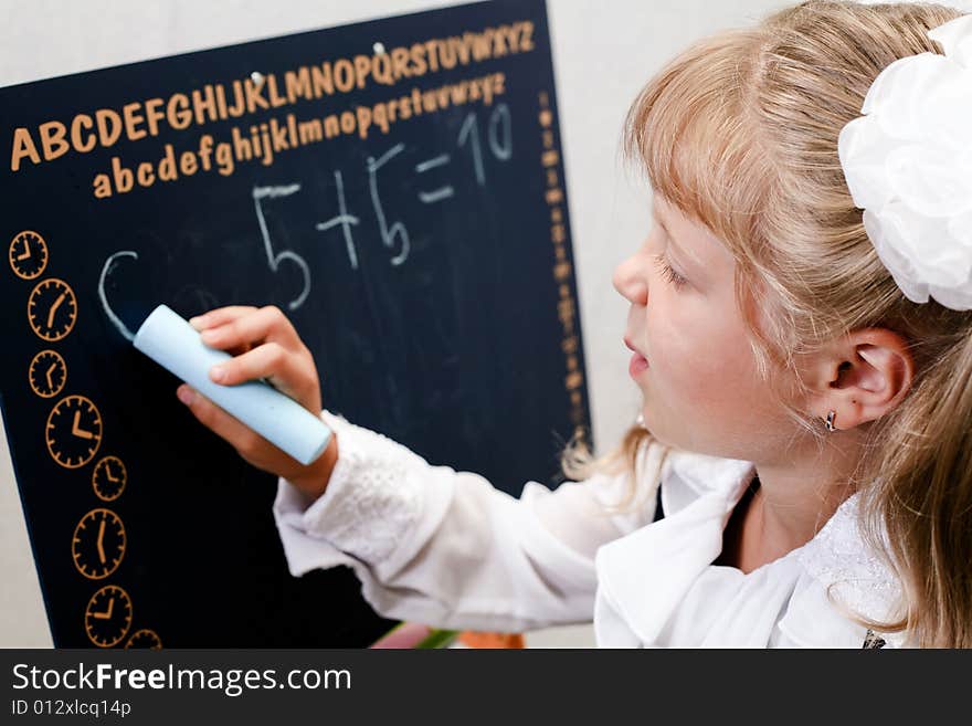 Little girl standing near blackboard. Writing on it. Little girl standing near blackboard. Writing on it.