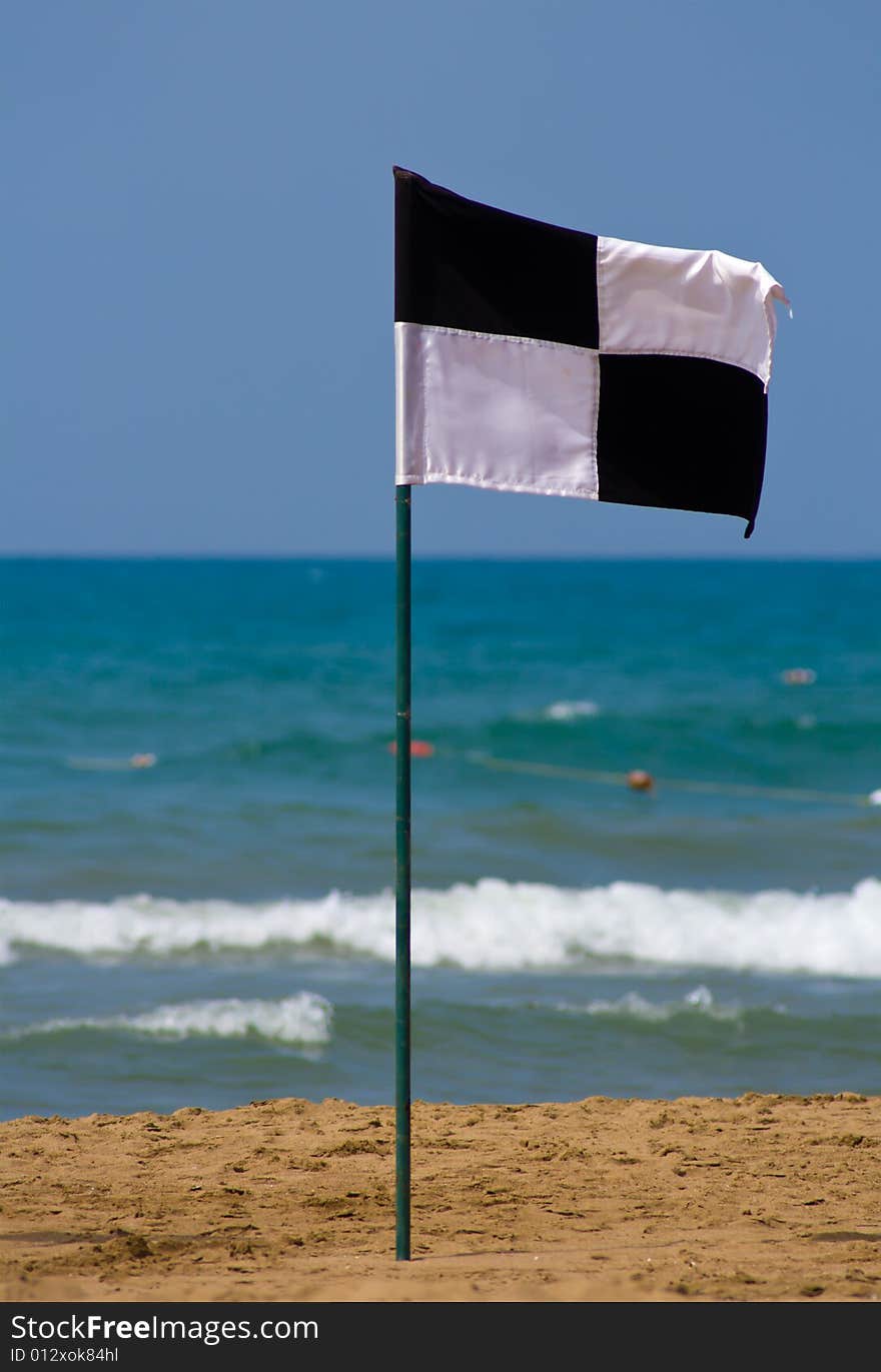 Quartered black and white flag on the beach, showing zoned off area