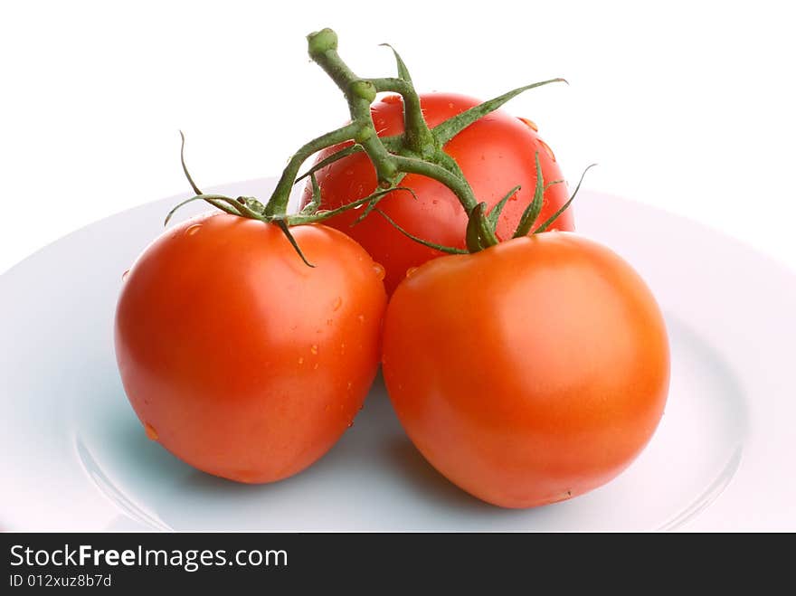 Three tomatoes on a plate isolated on white