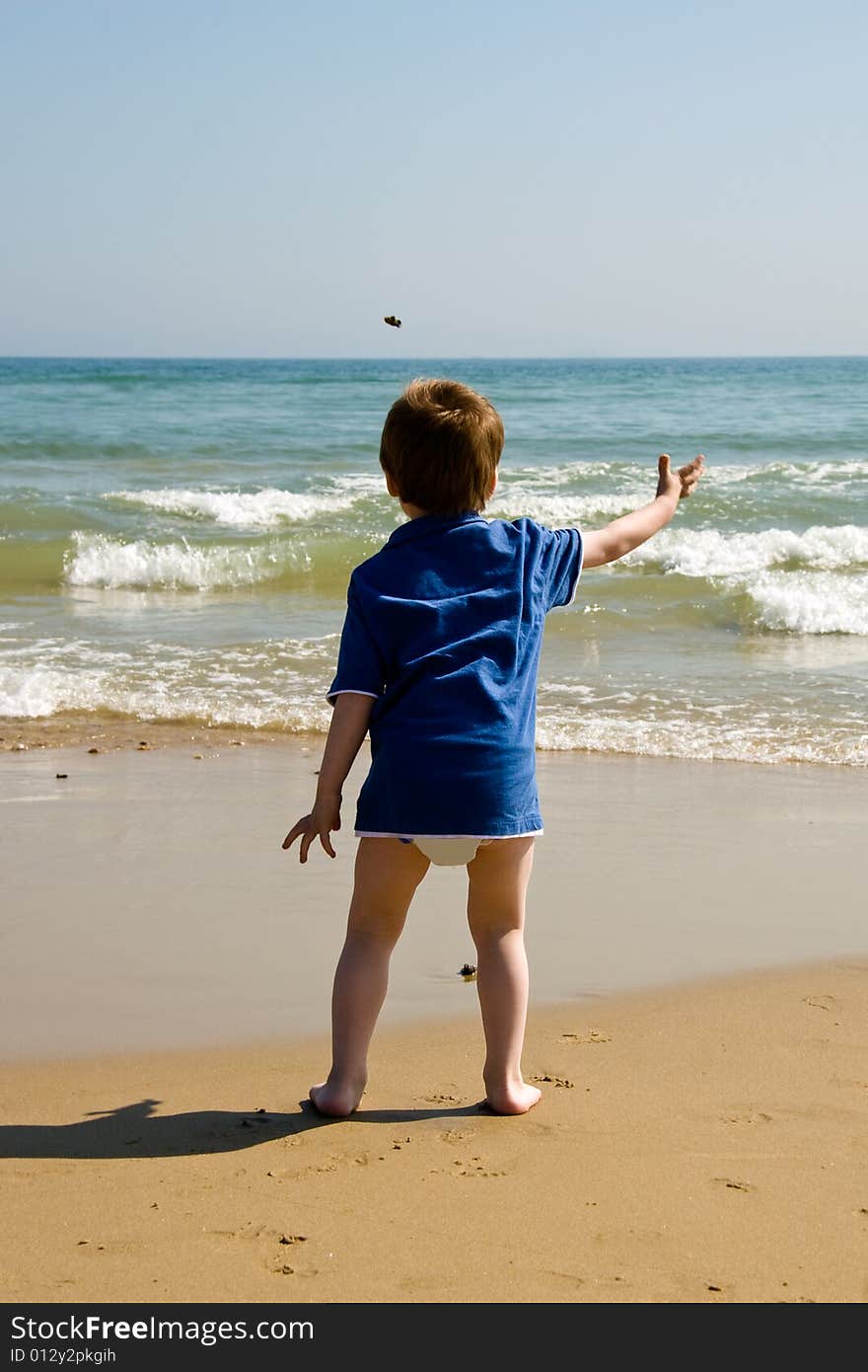 Little boy throwing stones into the sea. Little boy throwing stones into the sea