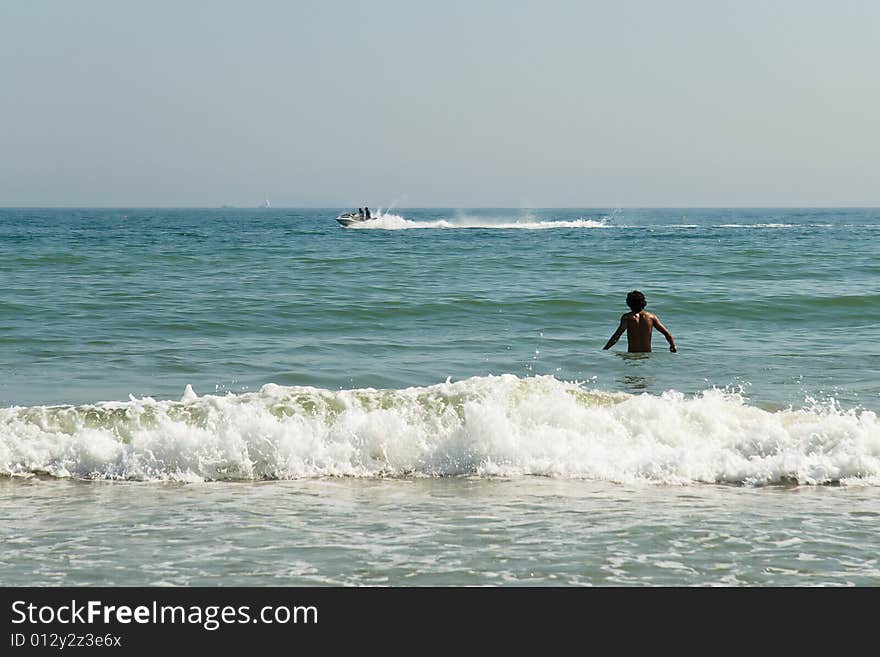 A young man walking into the summer sea. A young man walking into the summer sea