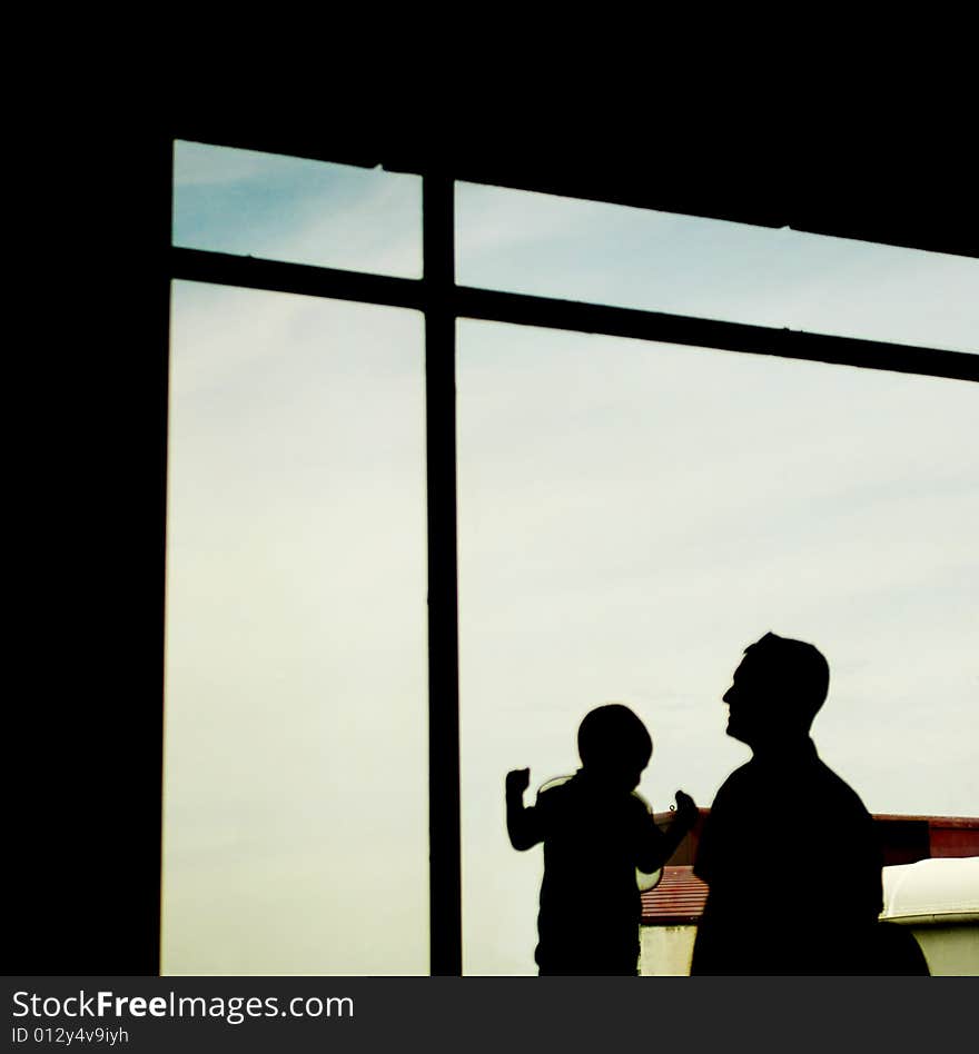 Silhouette of a father and his son at the window. Silhouette of a father and his son at the window