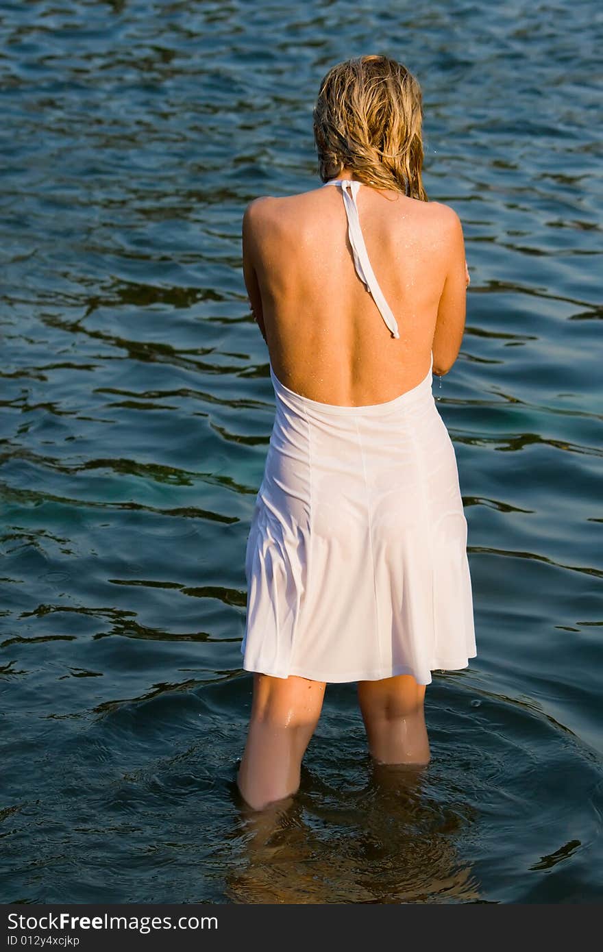 Girl in a white dress stands in water having turned a back. Girl in a white dress stands in water having turned a back