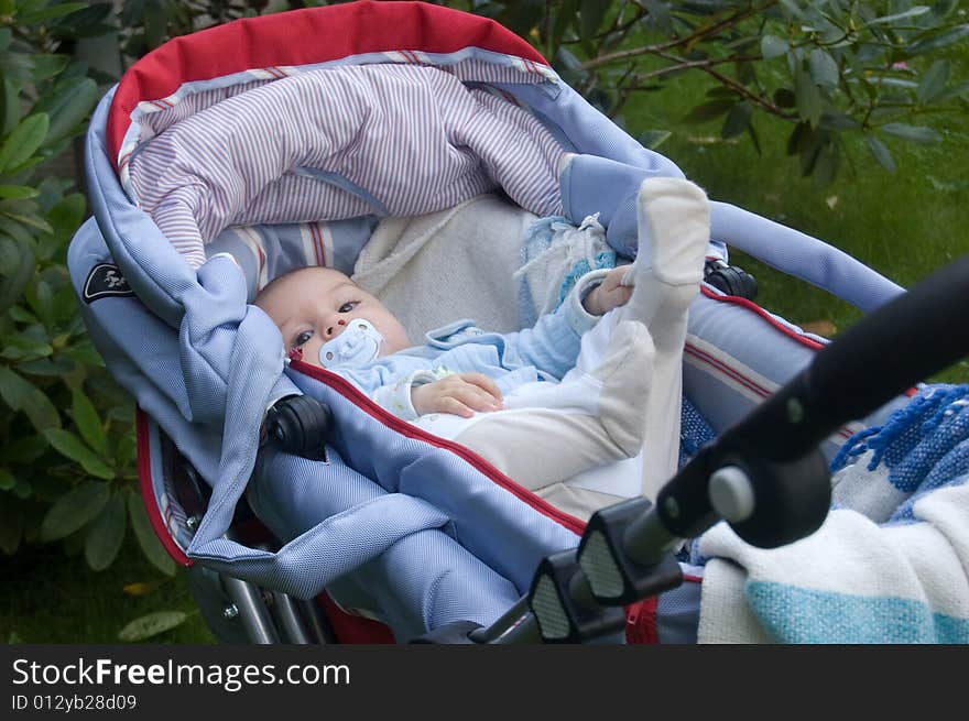 Four month baby-boy doing gymnastic in his perambulator, walking time outside. Four month baby-boy doing gymnastic in his perambulator, walking time outside