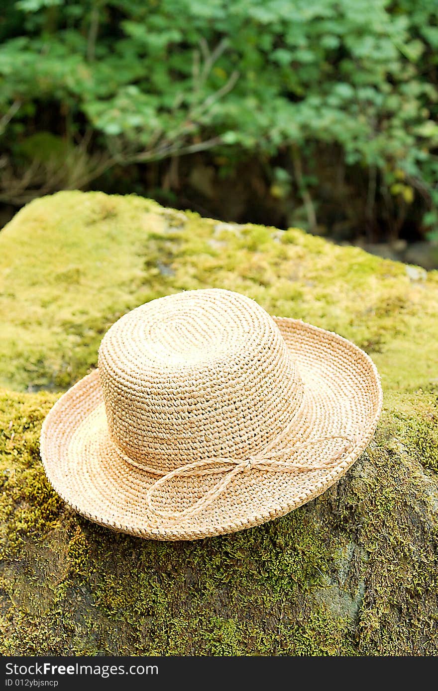 Straw raffia hat on rock in woods. Straw raffia hat on rock in woods