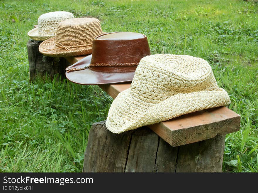 Straw and leather hats in a row on bench. Straw and leather hats in a row on bench