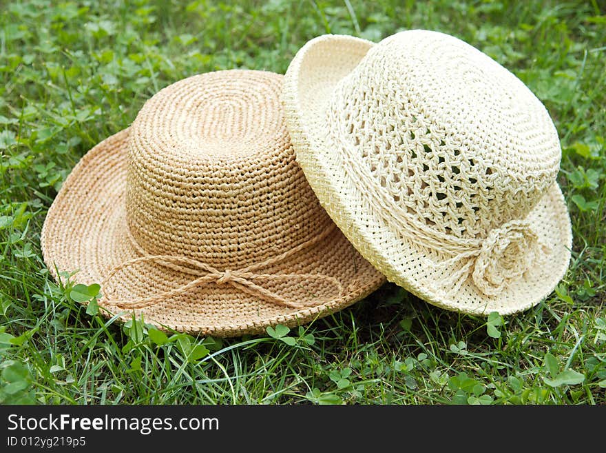 Pair of two straw raffia crocheted hats on grass. Pair of two straw raffia crocheted hats on grass