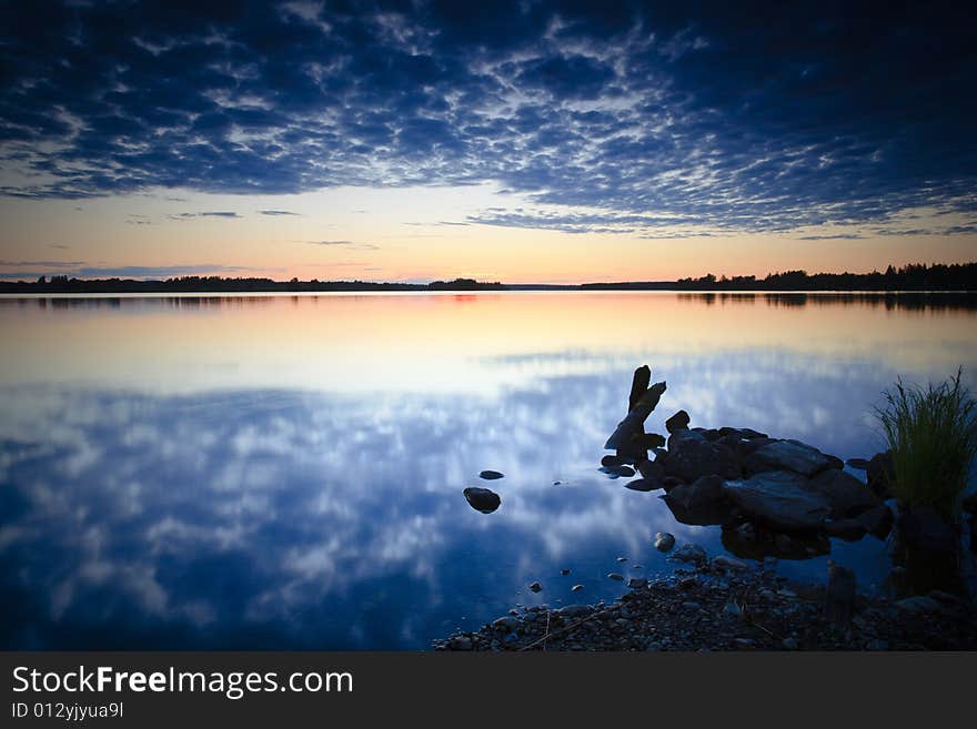 Sunset on rocky beach with cloud reflections