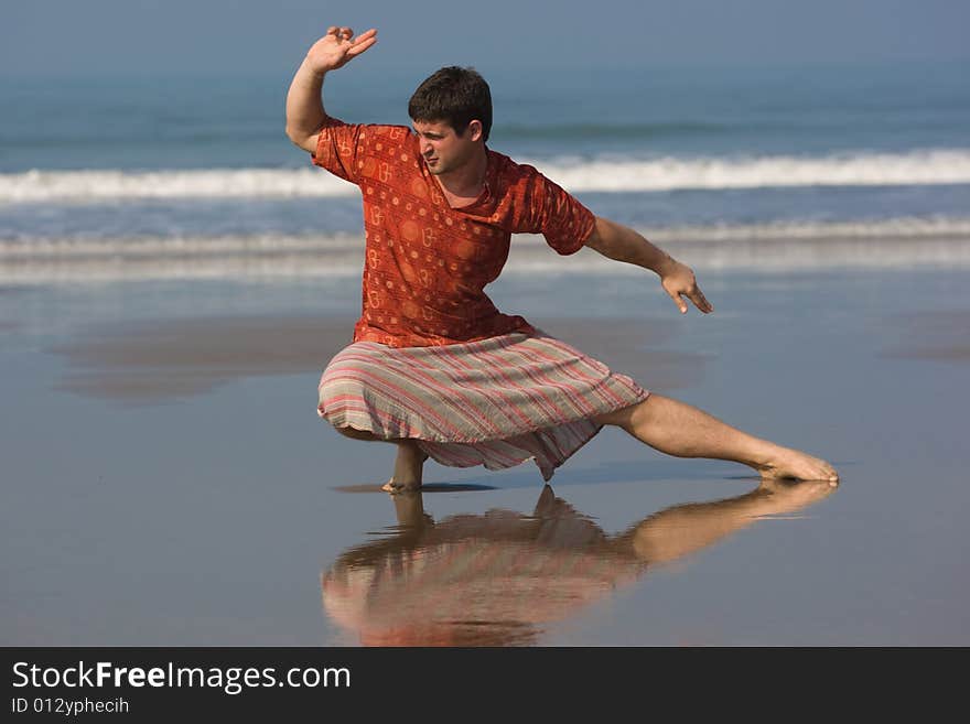 Man is doing east gymnastic on the beach in morning