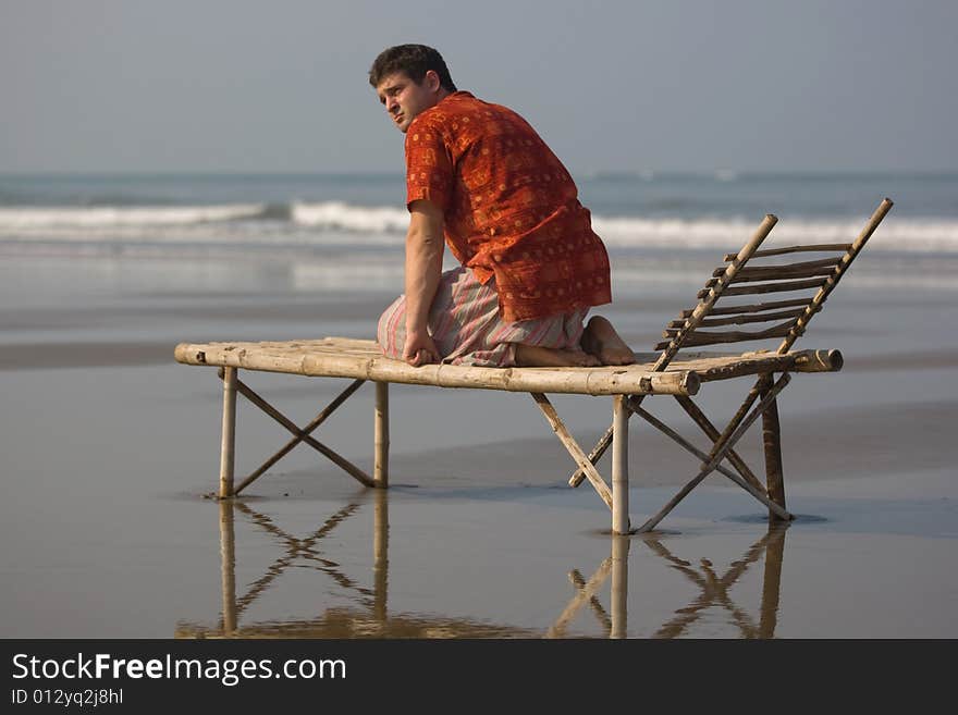 Man is siting on the trestle-bed on the beach. Man is siting on the trestle-bed on the beach