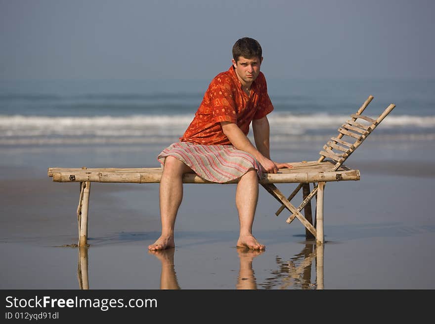 Man is siting on the trestle-bed on the beach. Man is siting on the trestle-bed on the beach