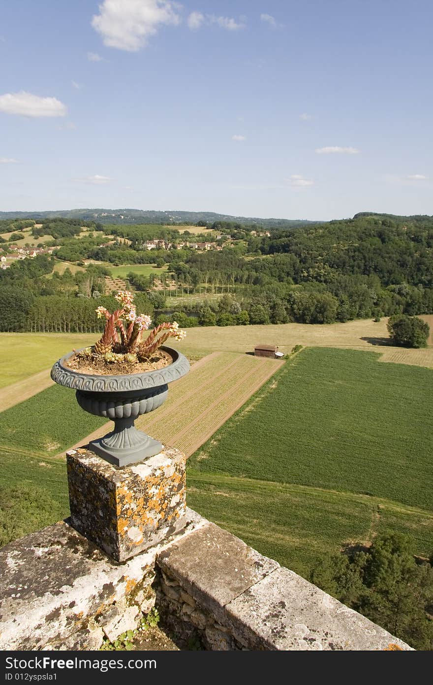 View over the fields of the Dordogne countryside with stone walls and flower pot in the foreground. View over the fields of the Dordogne countryside with stone walls and flower pot in the foreground