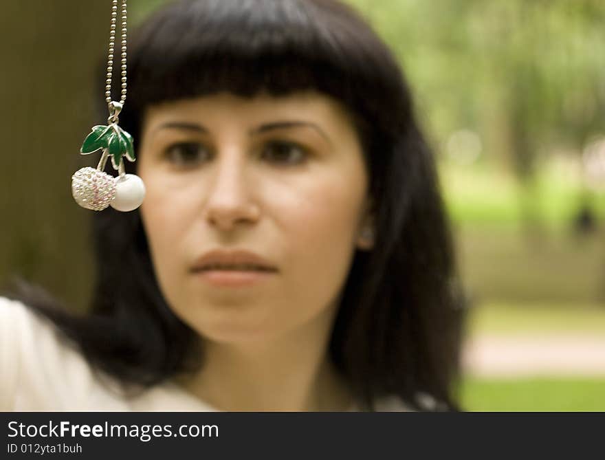 Outdoor portrait of pretty young brunette with jewelery cherry. girl out of focus.