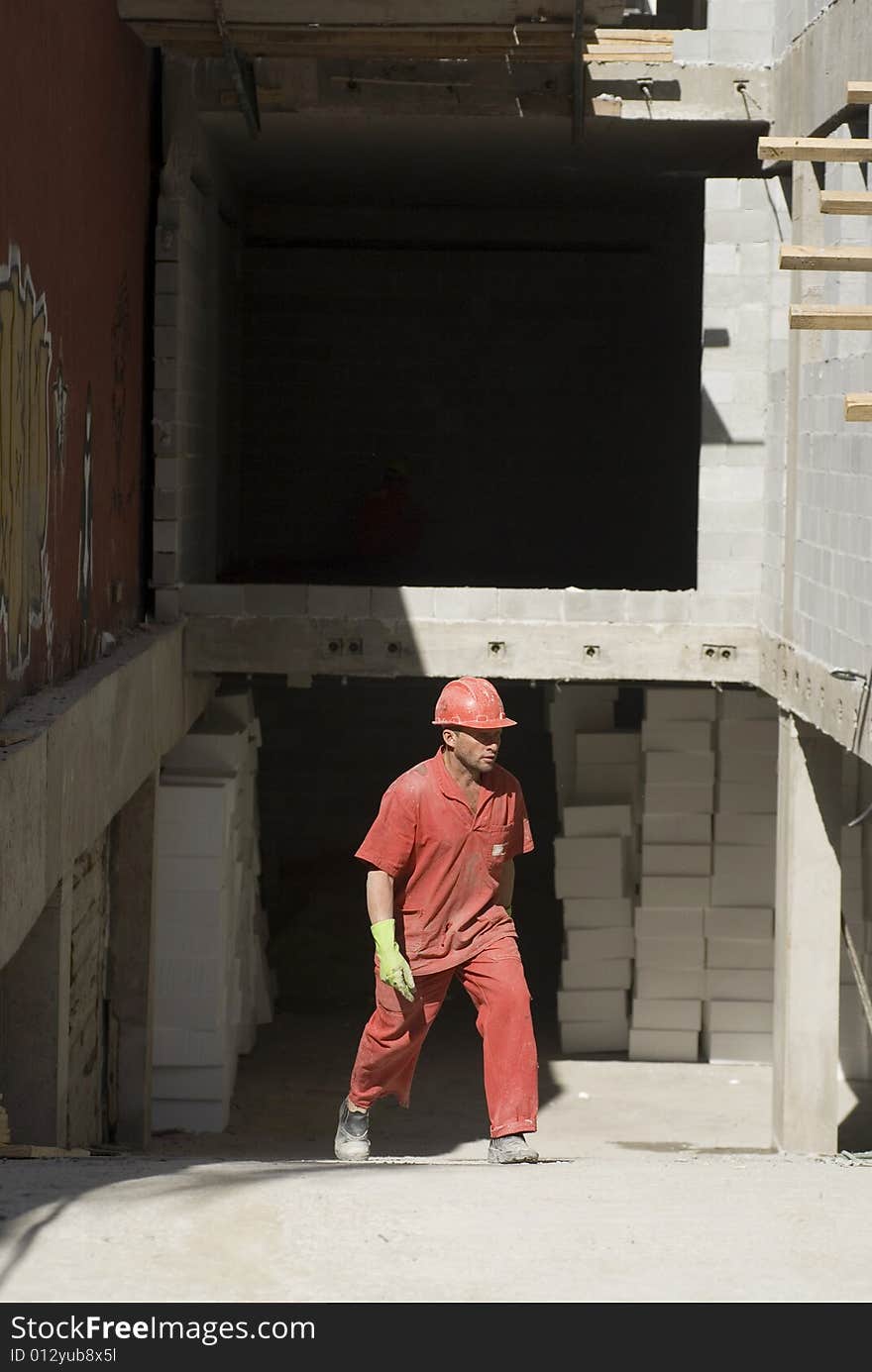 Worker Walks Across Jobsite - Vertical