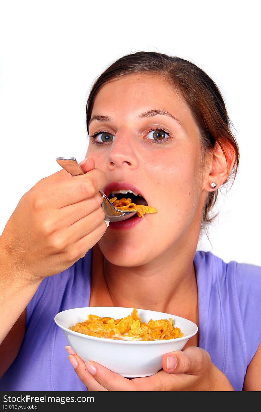 A young woman enjoys her crunchy cornflakes. Isolated over white. A young woman enjoys her crunchy cornflakes. Isolated over white.