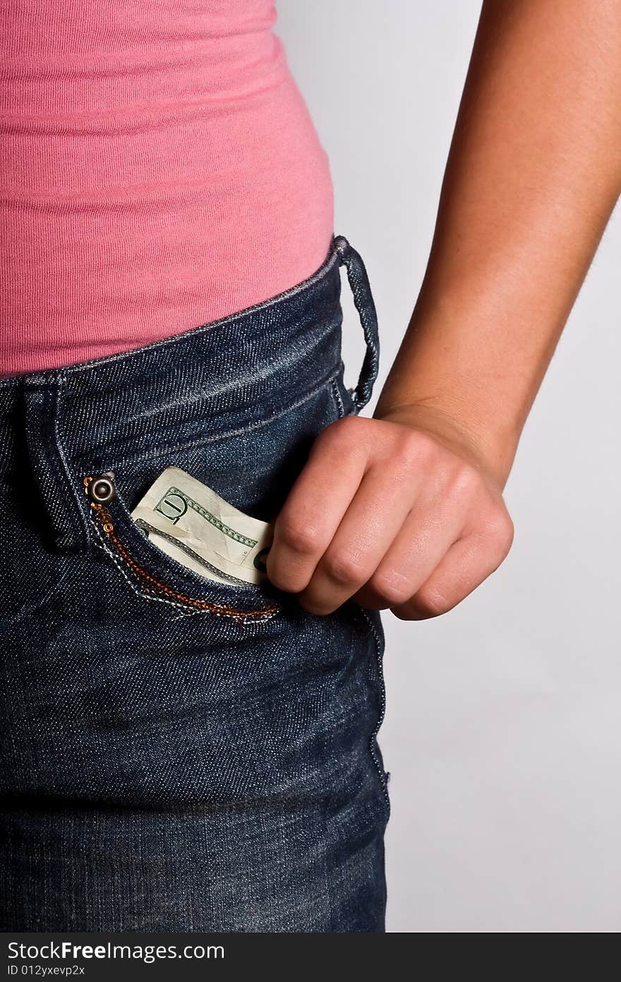 Teen girl with money to burn blue jeans and pink shirt stuffing money in front pocket. Teen girl with money to burn blue jeans and pink shirt stuffing money in front pocket