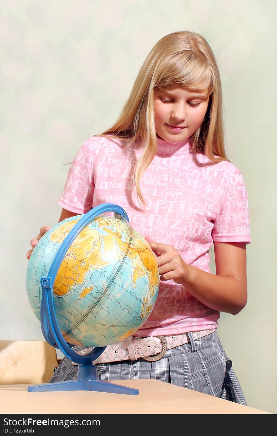 The schoolgirl studies the globe at a lesson at school. The schoolgirl studies the globe at a lesson at school