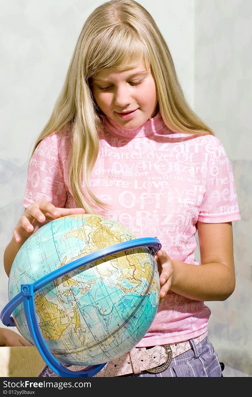 The schoolgirl studies the globe at a lesson at school. The schoolgirl studies the globe at a lesson at school