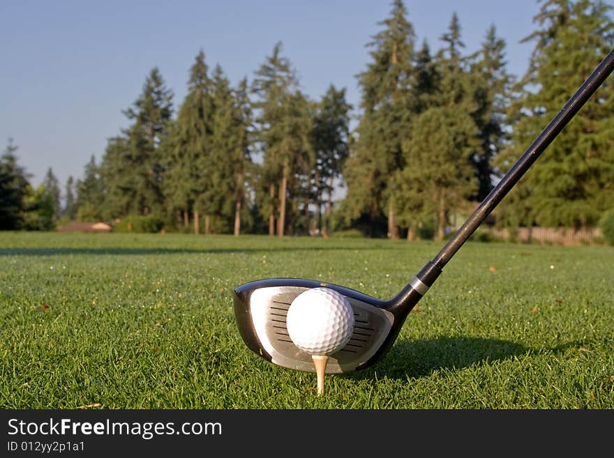 Head of golf club driver is aligned next to golf ball on tee. Horizontally framed photo. Head of golf club driver is aligned next to golf ball on tee. Horizontally framed photo.