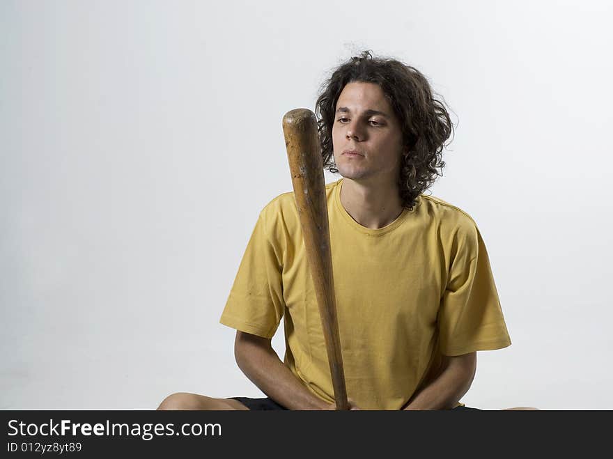 Man sitting cross legged looking at a baseball bat. Horizontally framed photograph. Man sitting cross legged looking at a baseball bat. Horizontally framed photograph