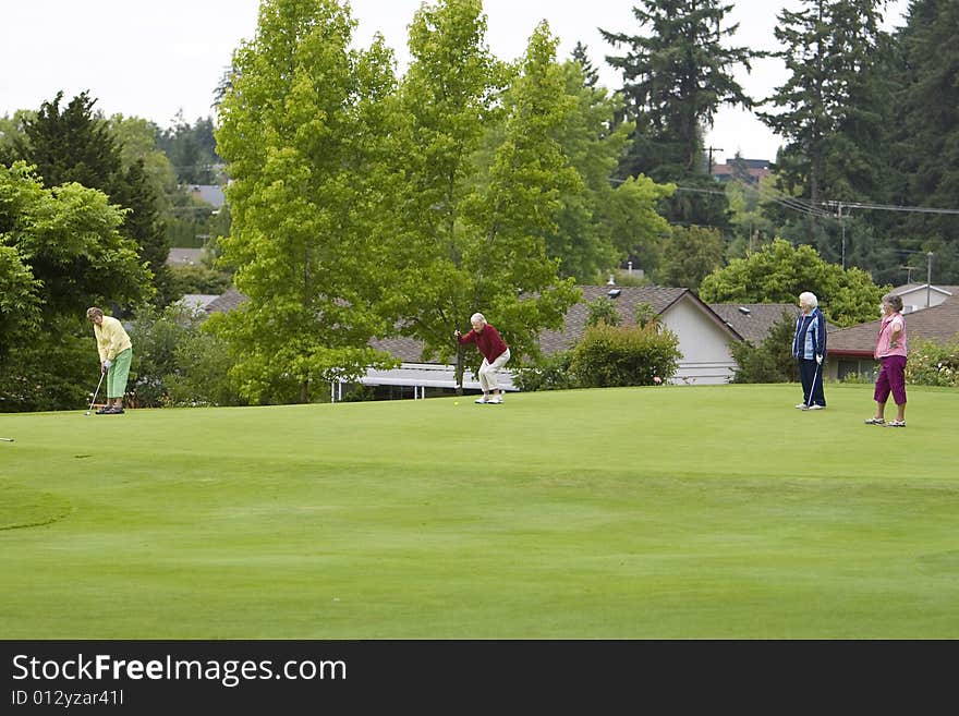 Group of four women playing golf. Horizontally framed photo.