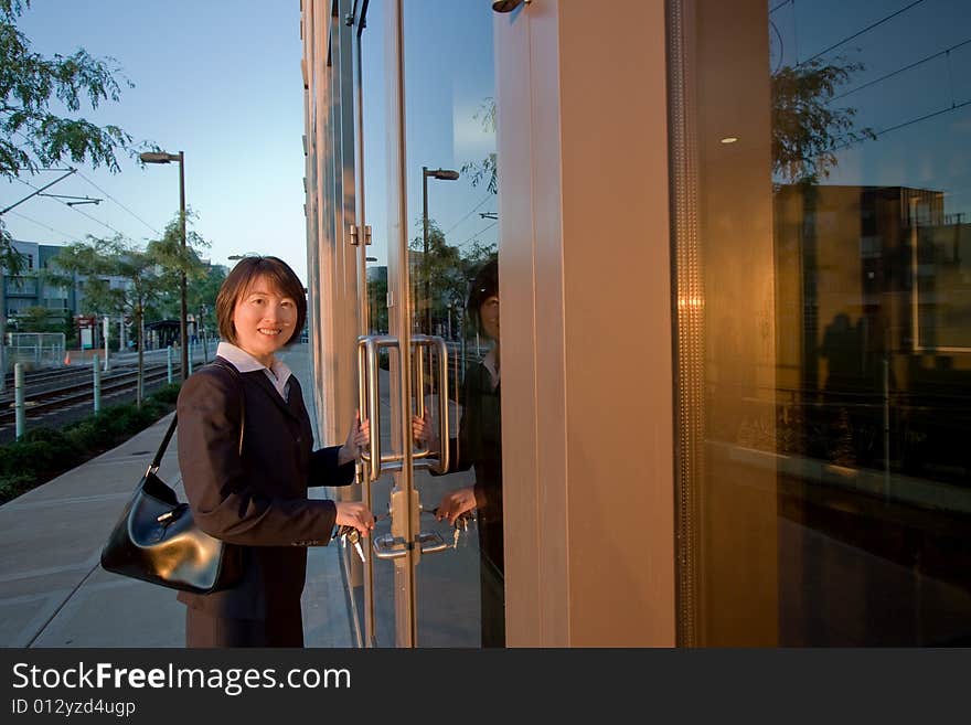 Woman wearing suit smiles at camera while opening door. She has a purse over her shoulder. Horizontally framed photo. Woman wearing suit smiles at camera while opening door. She has a purse over her shoulder. Horizontally framed photo.