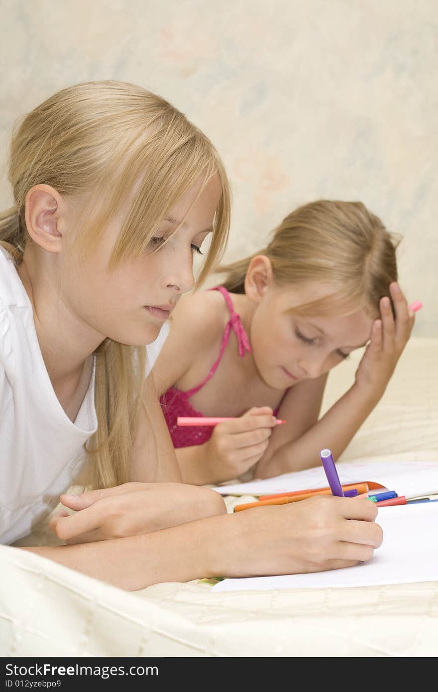 Two sisters do homework on sofa