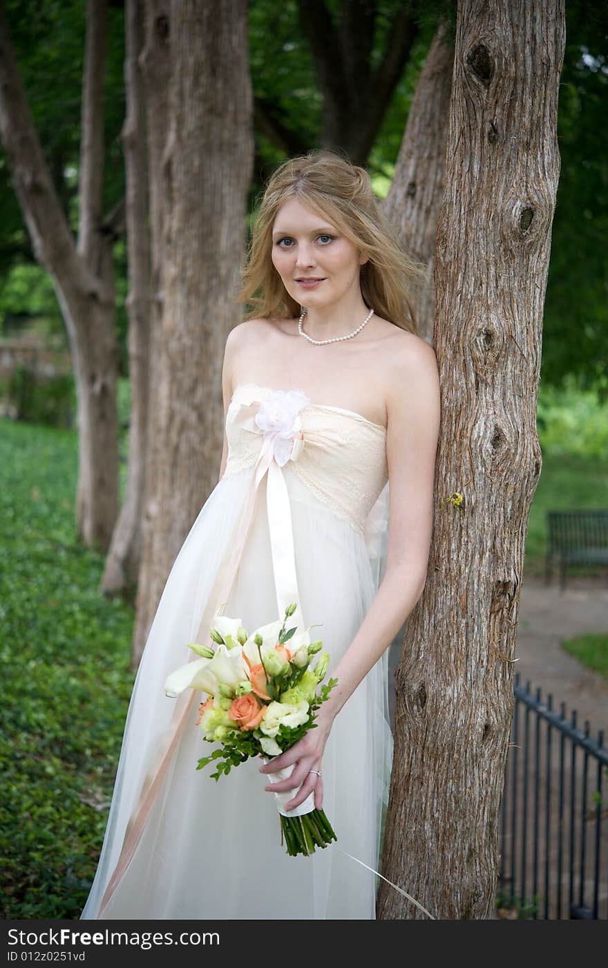 Natural bride leaning against a tree