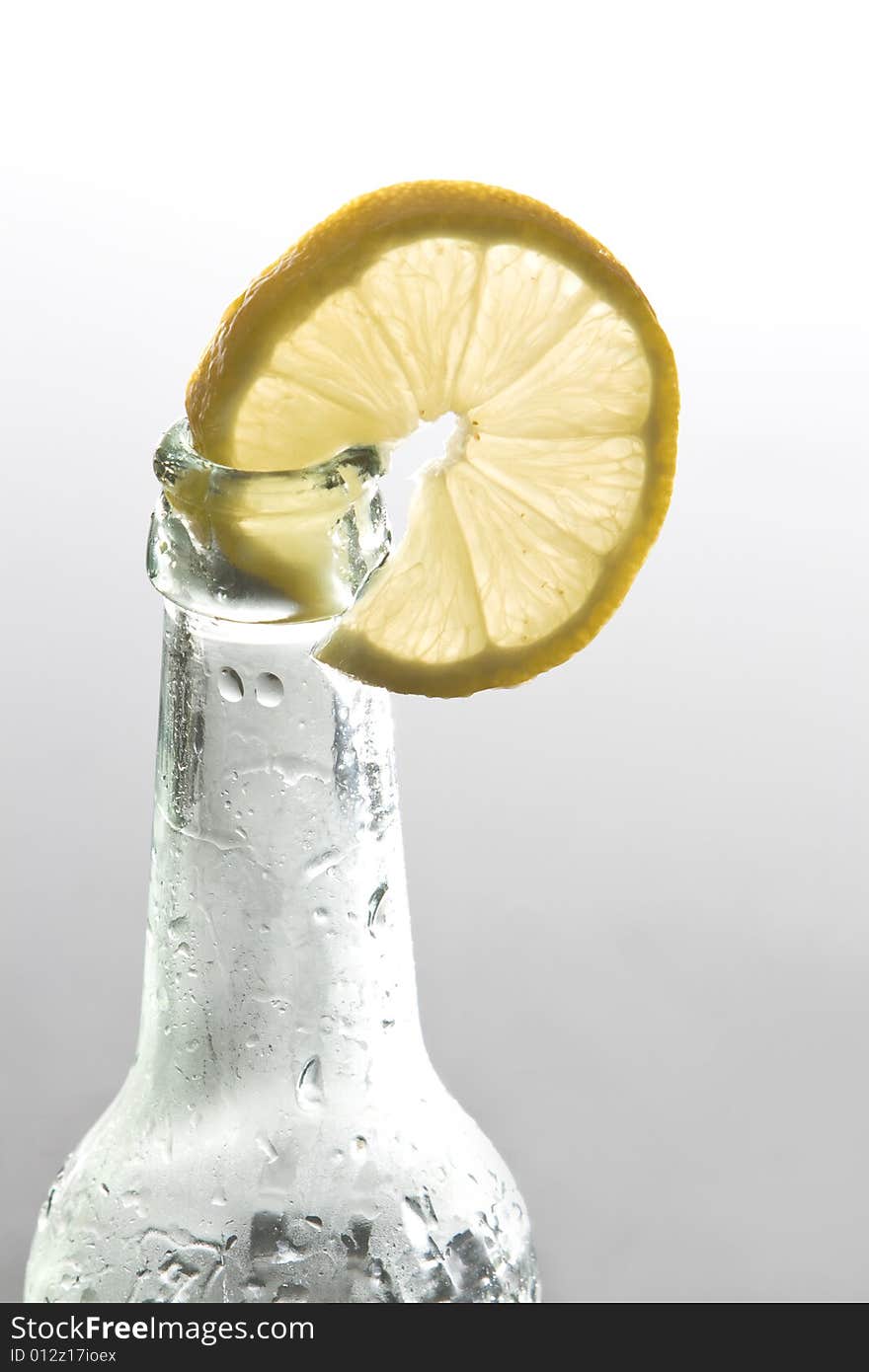 A lemon slice is decorating a bottle. A lemon slice is decorating a bottle.