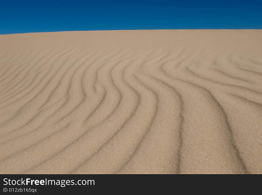 Rolling sand dunes on a bright blue sky