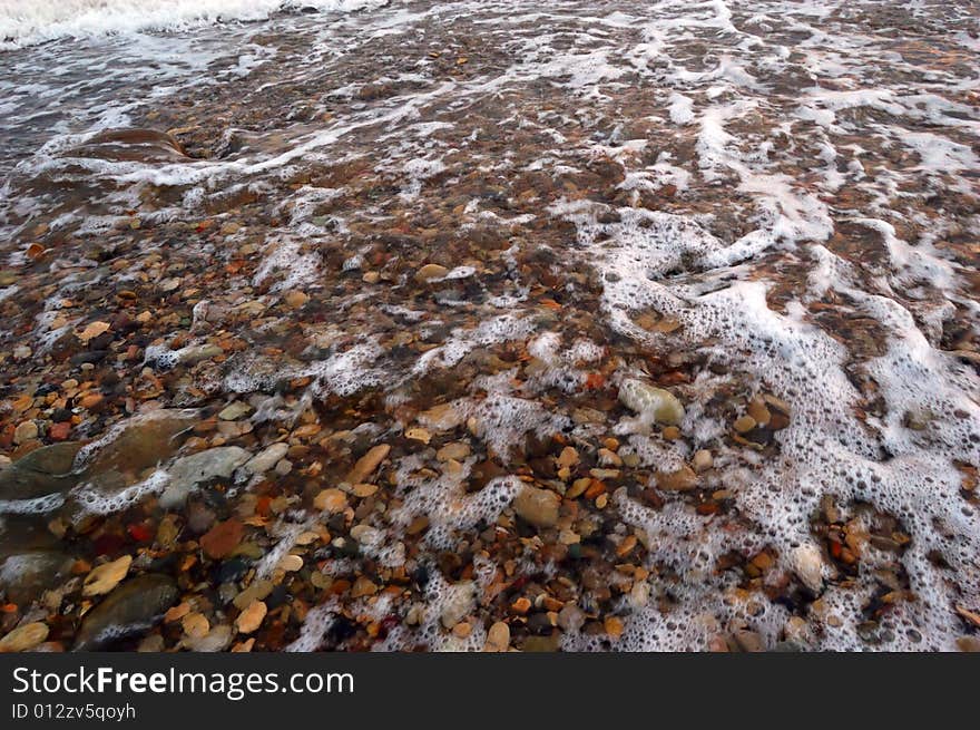 Closeup of sea shore with pebbles covered with film of water. Closeup of sea shore with pebbles covered with film of water