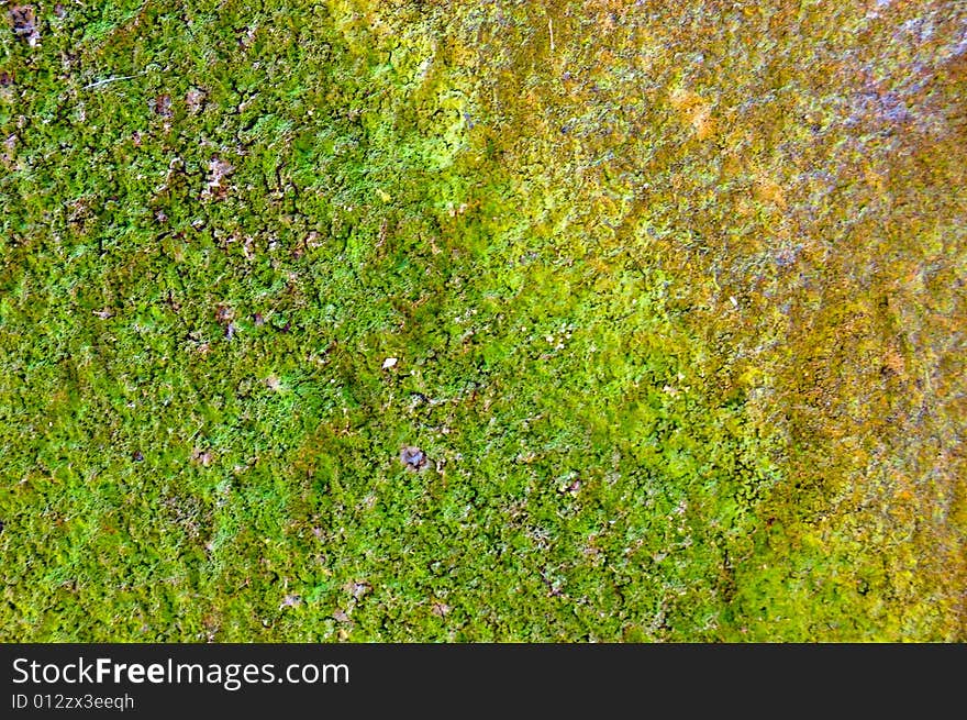 Colored (prevaling green and yellow) rough stone surface with lichen