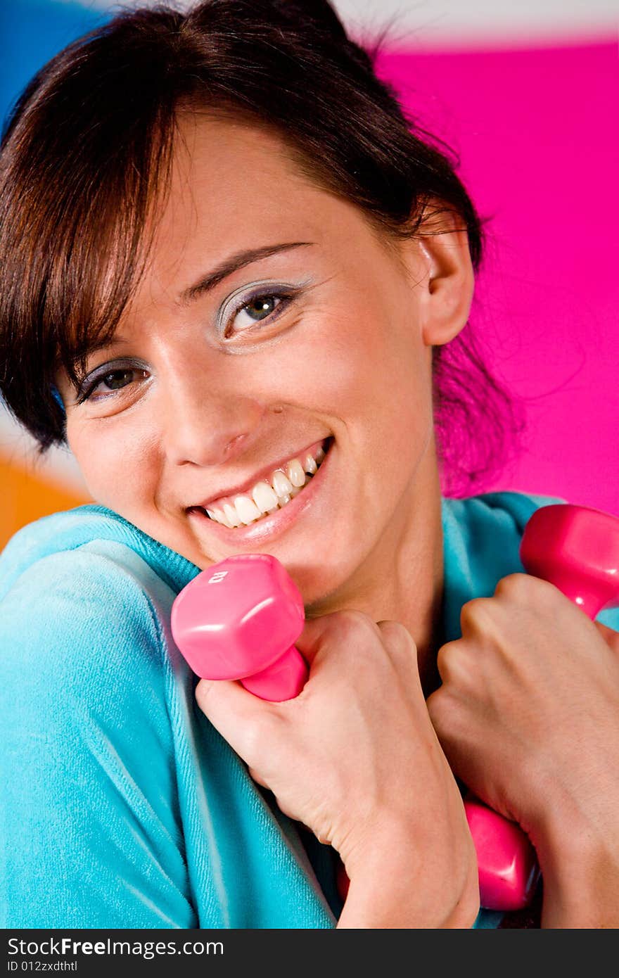 Beautiful young woman curls dumbbells with a happy smile. Beautiful young woman curls dumbbells with a happy smile.