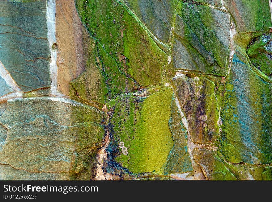 Colored (prevaling green) rough wall surface made of wild stones with lichen. Colored (prevaling green) rough wall surface made of wild stones with lichen