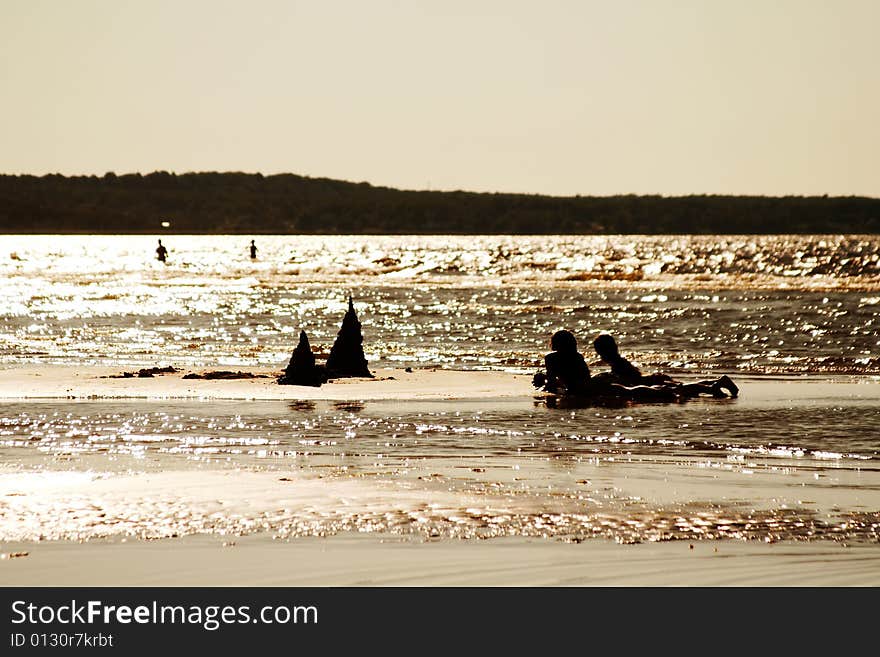 Silhouettes of children building a sandcastle on a beach. Silhouettes of children building a sandcastle on a beach