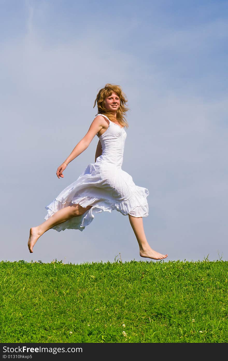 Girl runs on a grass on a background of the blue sky. Girl runs on a grass on a background of the blue sky