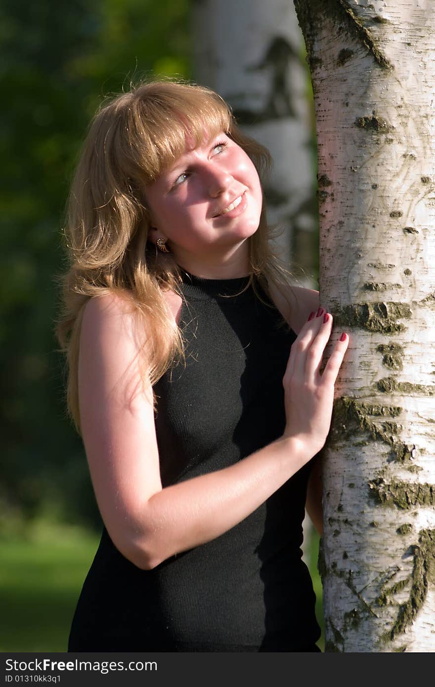 Beautiful girl in a black dress near to a tree. Beautiful girl in a black dress near to a tree