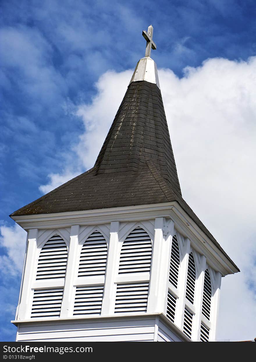 Conceptual view of church steeple against blue sky and white clouds