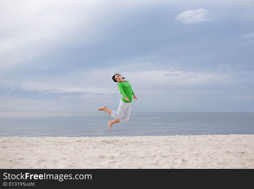 Attractive brunette woman jumping on the beach. Attractive brunette woman jumping on the beach