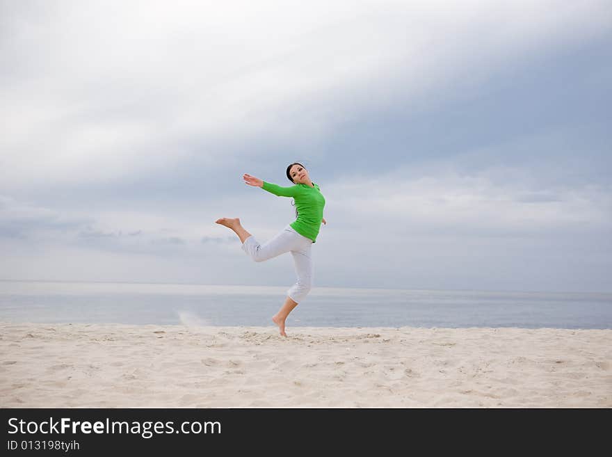 Attractive brunette woman jumping on the beach. Attractive brunette woman jumping on the beach