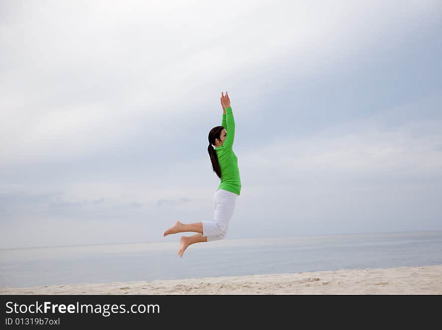 Attractive brunette woman jumping on the beach. Attractive brunette woman jumping on the beach