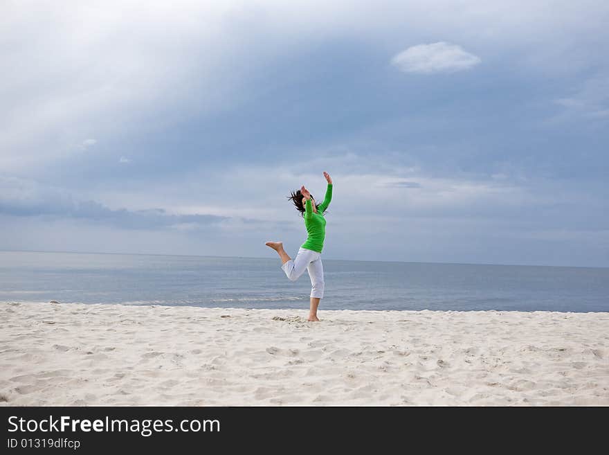 Attractive brunette woman jumping on the beach. Attractive brunette woman jumping on the beach