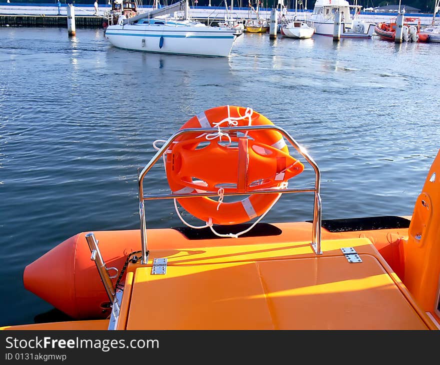 Details of the orange life-saving equipment on board rescue motor boat. Yachts in background.