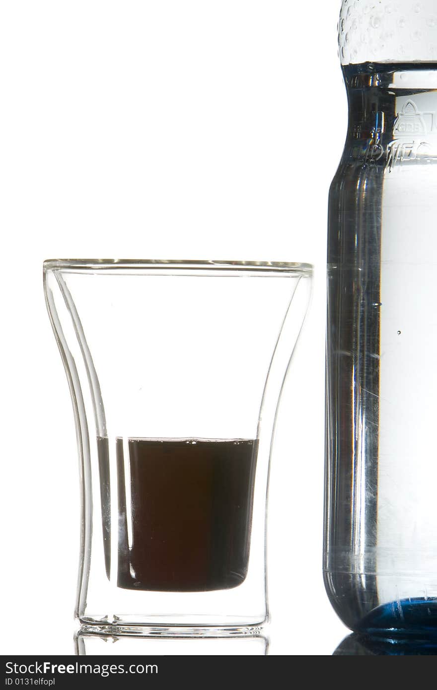 A waterbottle next to a glass with a drink