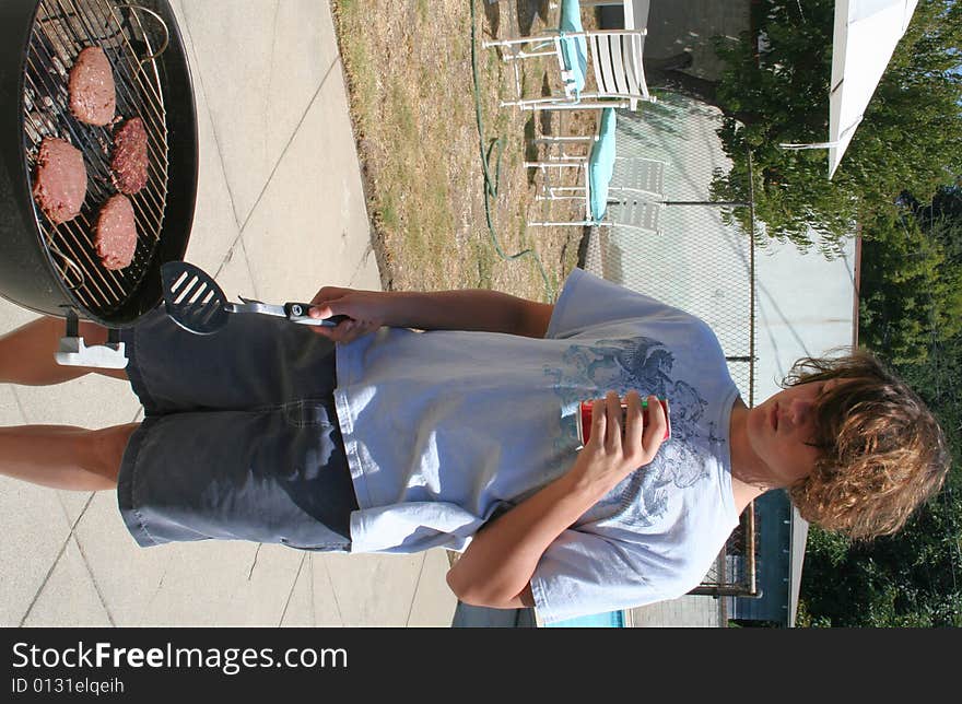 Young man flipping burgers by a barbecue. Young man flipping burgers by a barbecue.